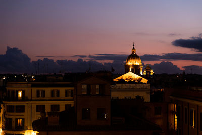 Illuminated buildings against sky at sunset