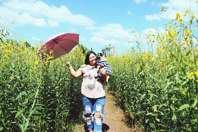 Woman holding umbrella standing against plants
