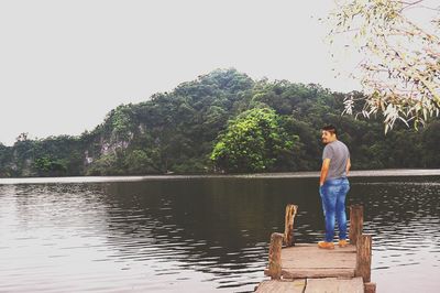 Man standing by lake against clear sky