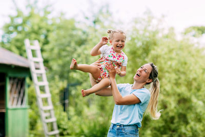 A young mother and her cute little girl are having fun in a sunny garden. the concept of a happy 