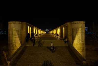 People walking on illuminated street at night