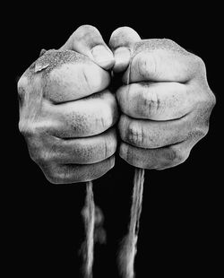 Cropped hands of man holding sand against black background