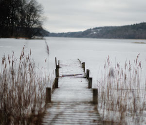 Wooden pier over lake against sky