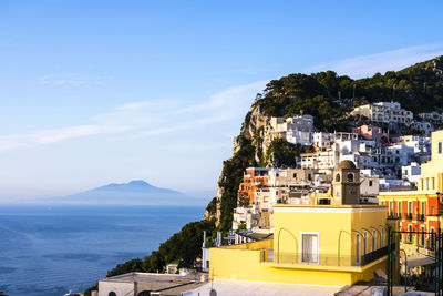 Buildings by sea against blue sky