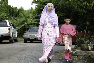 Full length of smiling siblings walking on road