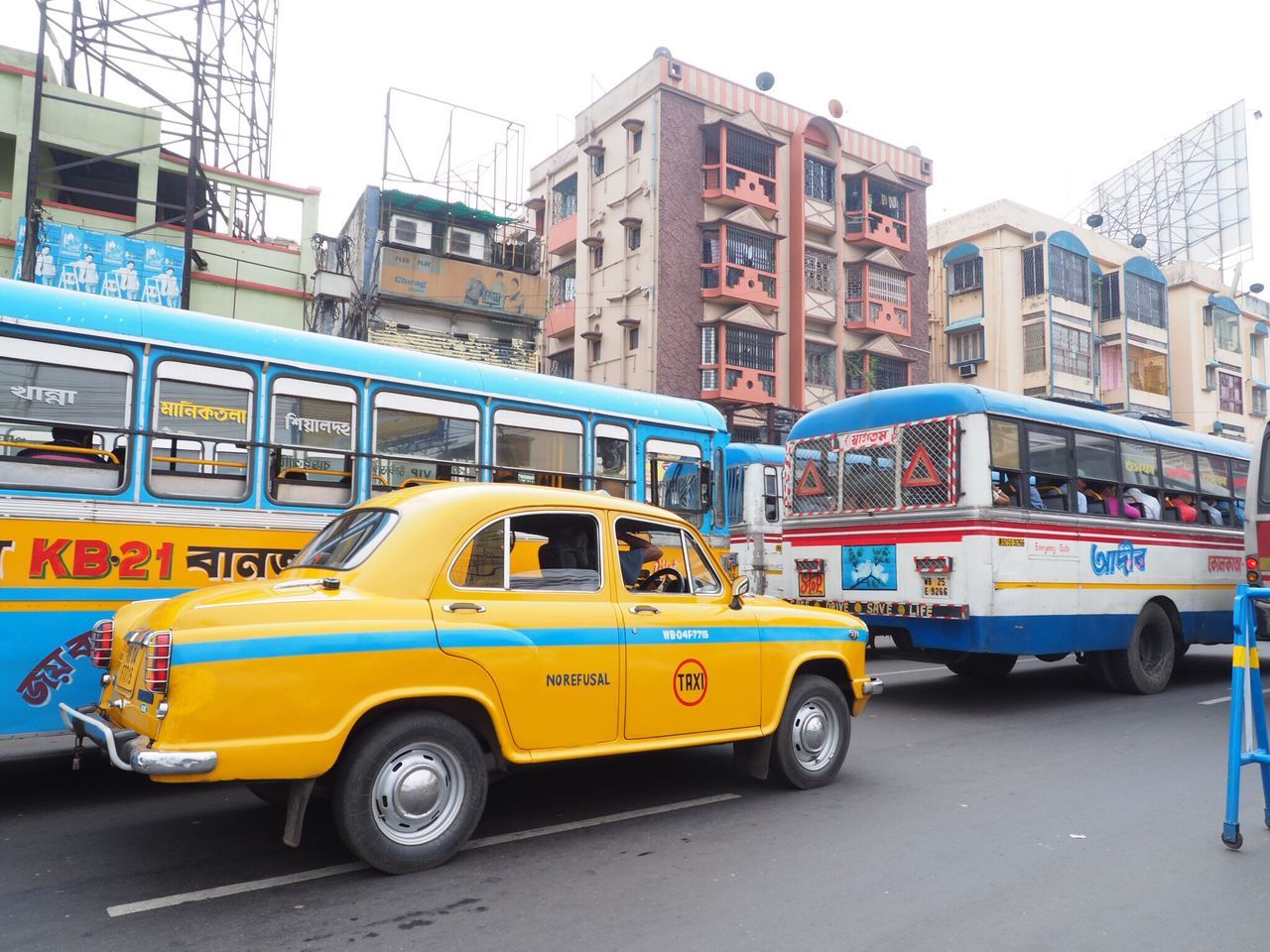 mode of transport, transportation, building exterior, land vehicle, architecture, built structure, street, car, public transportation, day, city, outdoors, stationary, yellow, road, no people