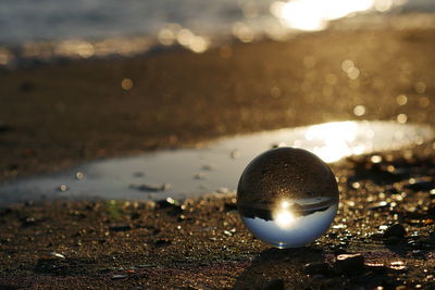 High angle view of crystal ball with reflection at beach during sunset