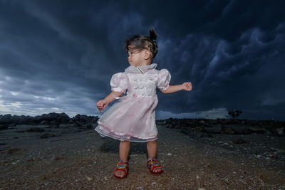 Girl standing on rock against sky