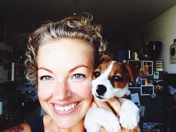 Close-up of smiling woman with puppy at home
