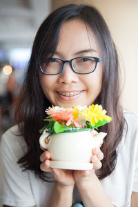 Close-up of smiling young woman holding flowers