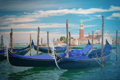 Gondolas moored on canal against church of san giorgio maggiore