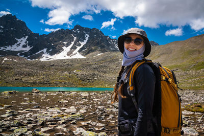 Portrait of a smiling young woman. in the background is a quiet lake and a mountain range. traveler