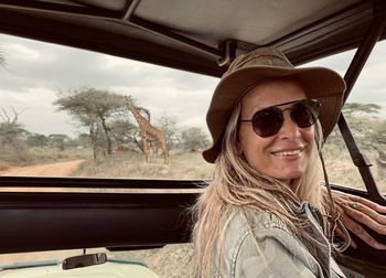 Side view portrait of smiling woman in safari vehicle at national park