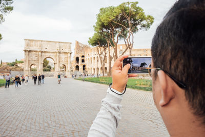 Side view of man photographing through camera at the colosseum