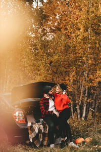 A romantic couple in love in warm sweaters is walking traveling by car in the autumn forest in fall