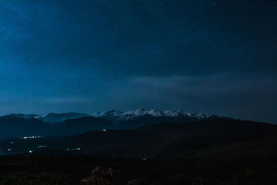 Scenic view of snowcapped mountains against sky at night