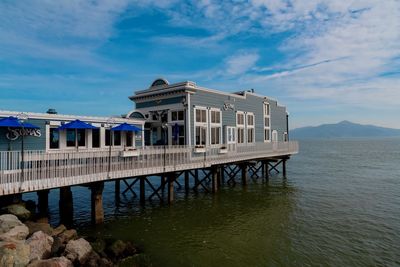 Building by sea against cloudy sky