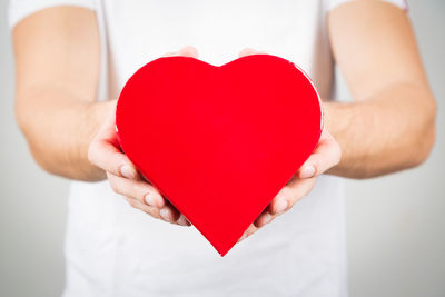 Midsection of man holding heart shape at home