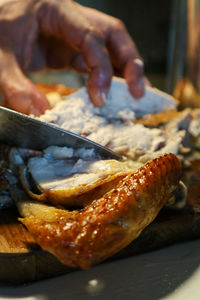 Close-up of hand holding meat on barbecue grill