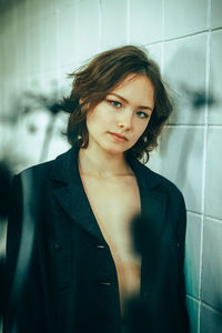 Portrait of young woman standing against wall