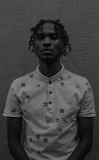 Portrait of young man standing against wall