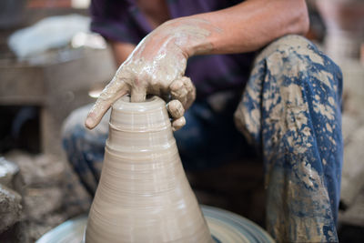 Midsection of woman making clay pot in workshop