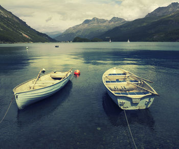 Boats moored on lake against mountains