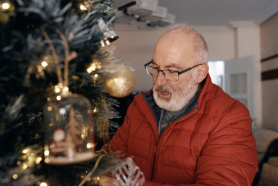 Grandparents decorate the christmas tree with their little granddaughter