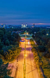 High angle view of illuminated city by sea against blue sky