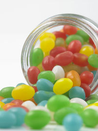 Multi colored candies spilling from jar against white background