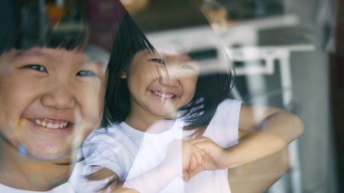 Multiple image of smiling girl with reflection on glass