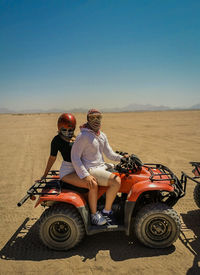 Side view of man and woman riding in desert sunny day clear sky