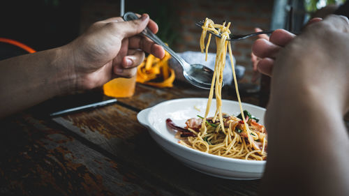 Midsection of person eating noodles on table