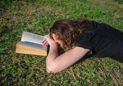 Woman lying with book on grass