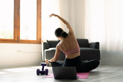 Rear view of woman stretching at home