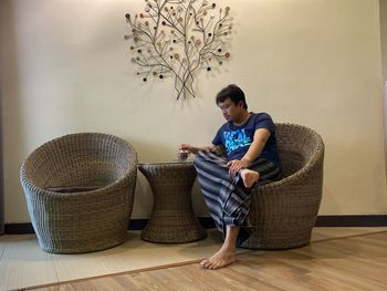 Full length of man sitting in basket at home