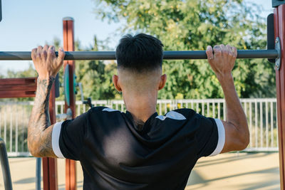 Boy doing push-ups with both arms on an iron bar