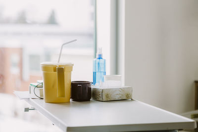 Items on bedside table in hospital room with window in background