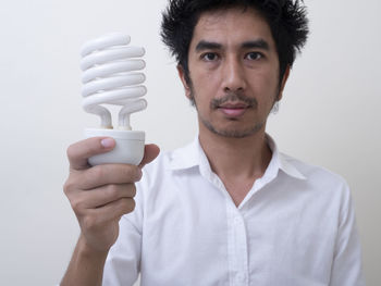 Portrait of young man holding camera over white background