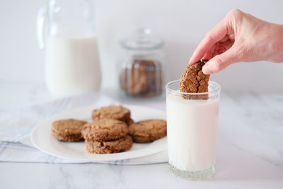 Woman's hand dipping homemade cookies into a glass of milk