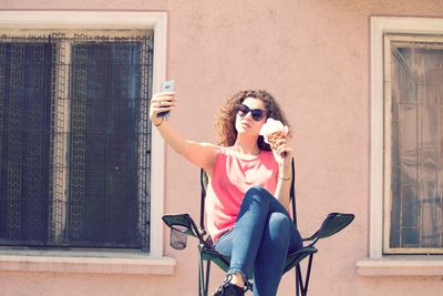 Young woman taking selfie while holding ice cream cone in city