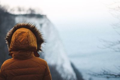 Rear view of woman wearing warm clothing while looking at mountain during winter