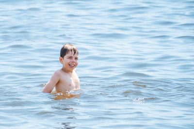 Portrait of shirtless man swimming in sea
