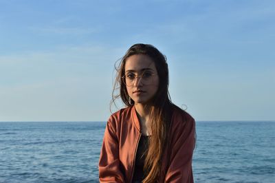 Young woman by sea against sky