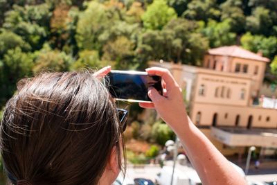 Rear view of woman photographing from smart phone