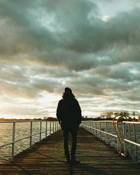 Rear view of silhouette man standing on pier