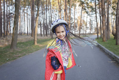 Portrait of woman standing on road amidst trees in forest