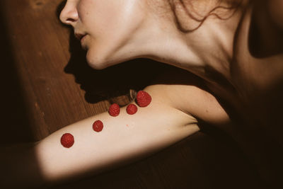 High angle view of mid adult woman with raspberries on hand lying at home