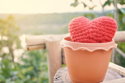 Close-up of knitted heart in terracotta pot on tree stump