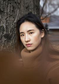 Portrait of beautiful young woman with tree trunk